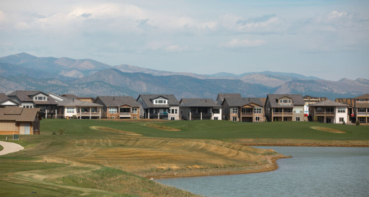 Suburban houses by golf course, pond, and distant mountains.