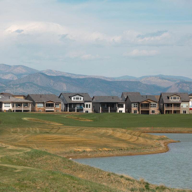 Suburban houses by golf course, pond, and distant mountains.