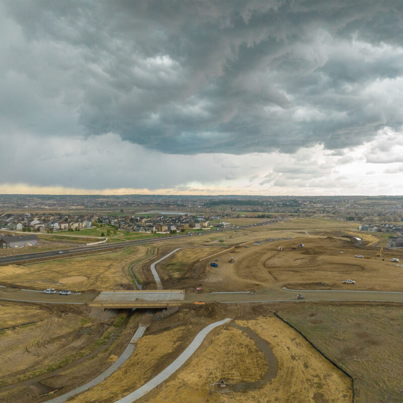 Aerial view of suburb, bridge construction, roads, clouds overhead.