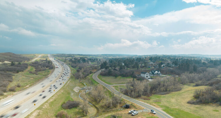 Aerial view: busy highway left, quiet rural road right.