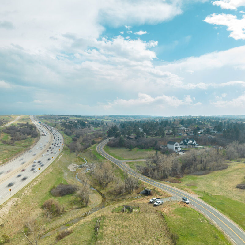 Aerial view: busy highway left, quiet rural road right.
