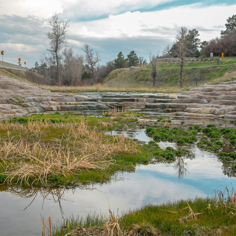 Sloped concrete water channel with grass.