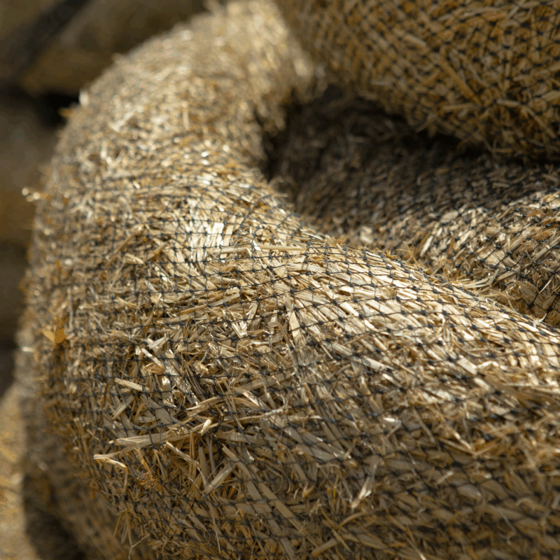 Coiled straw wattles wrapped in netting for erosion control.