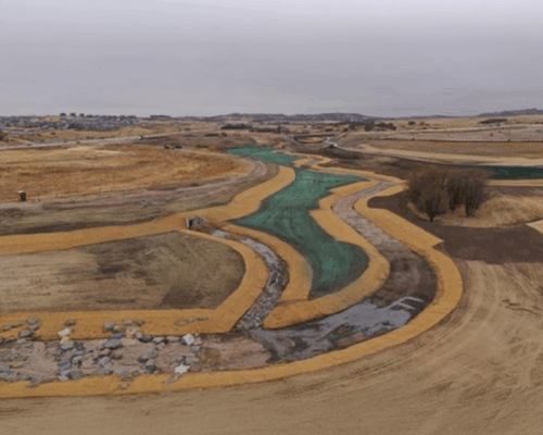 Unfinished canal cuts through dry, barren land under clouds.