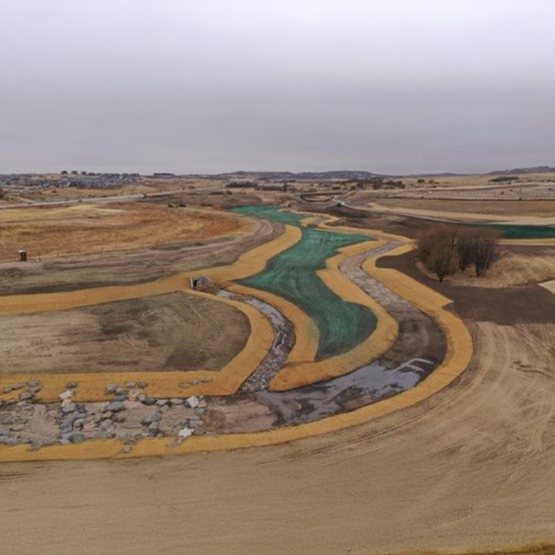Unfinished canal cuts through dry, barren land under clouds.