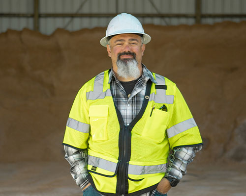 Man in hard hat and vest smiles.